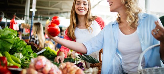 Young happy women shopping vegetables and fruits on the market
